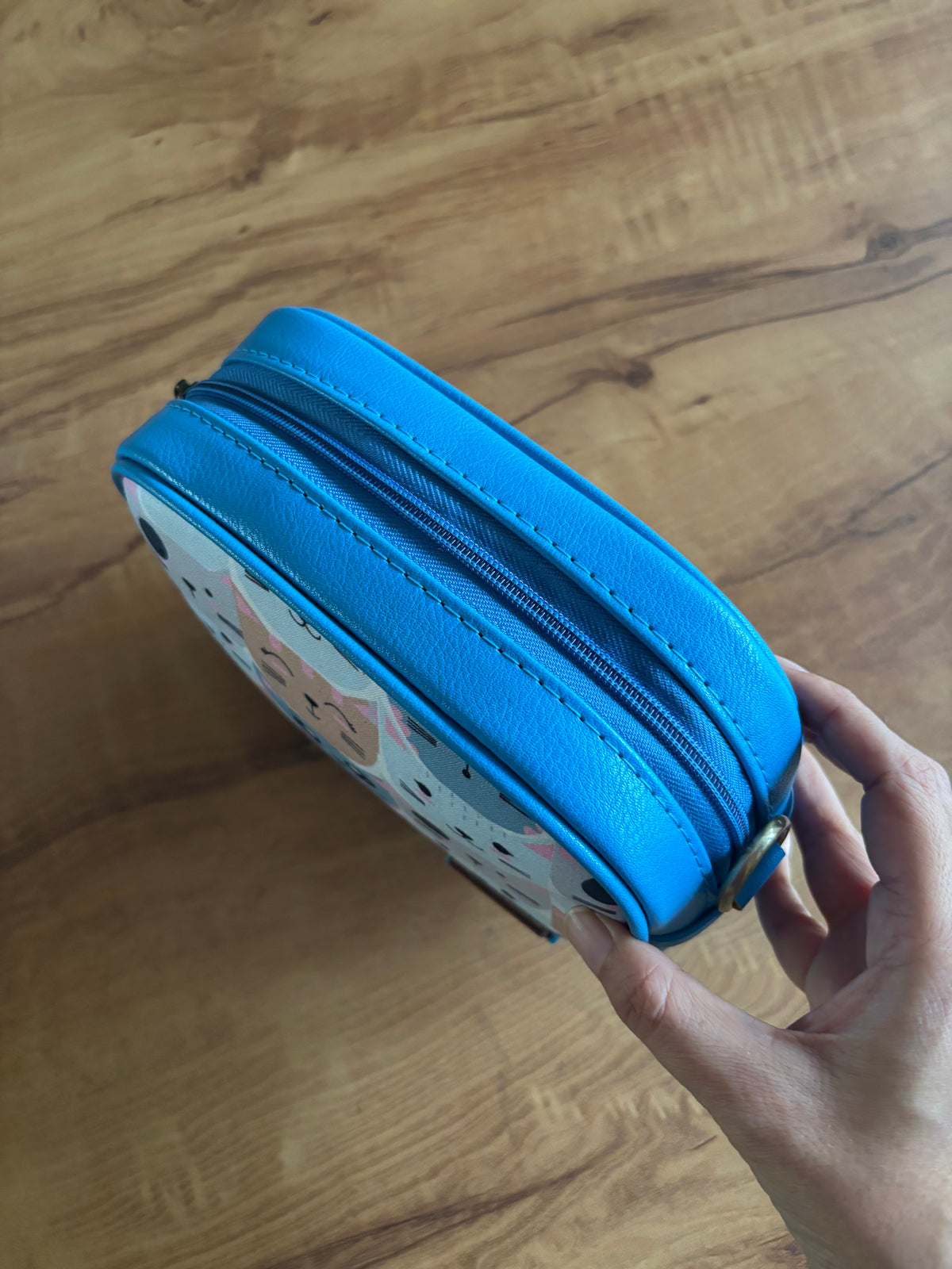 Pastel Cat Print Sling from the side, showing the blue faux leather and zip
