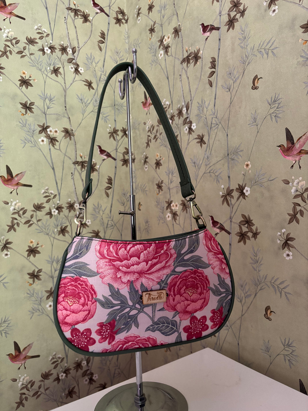 Peony Garden Baguette Bag hanging by its sage green strap