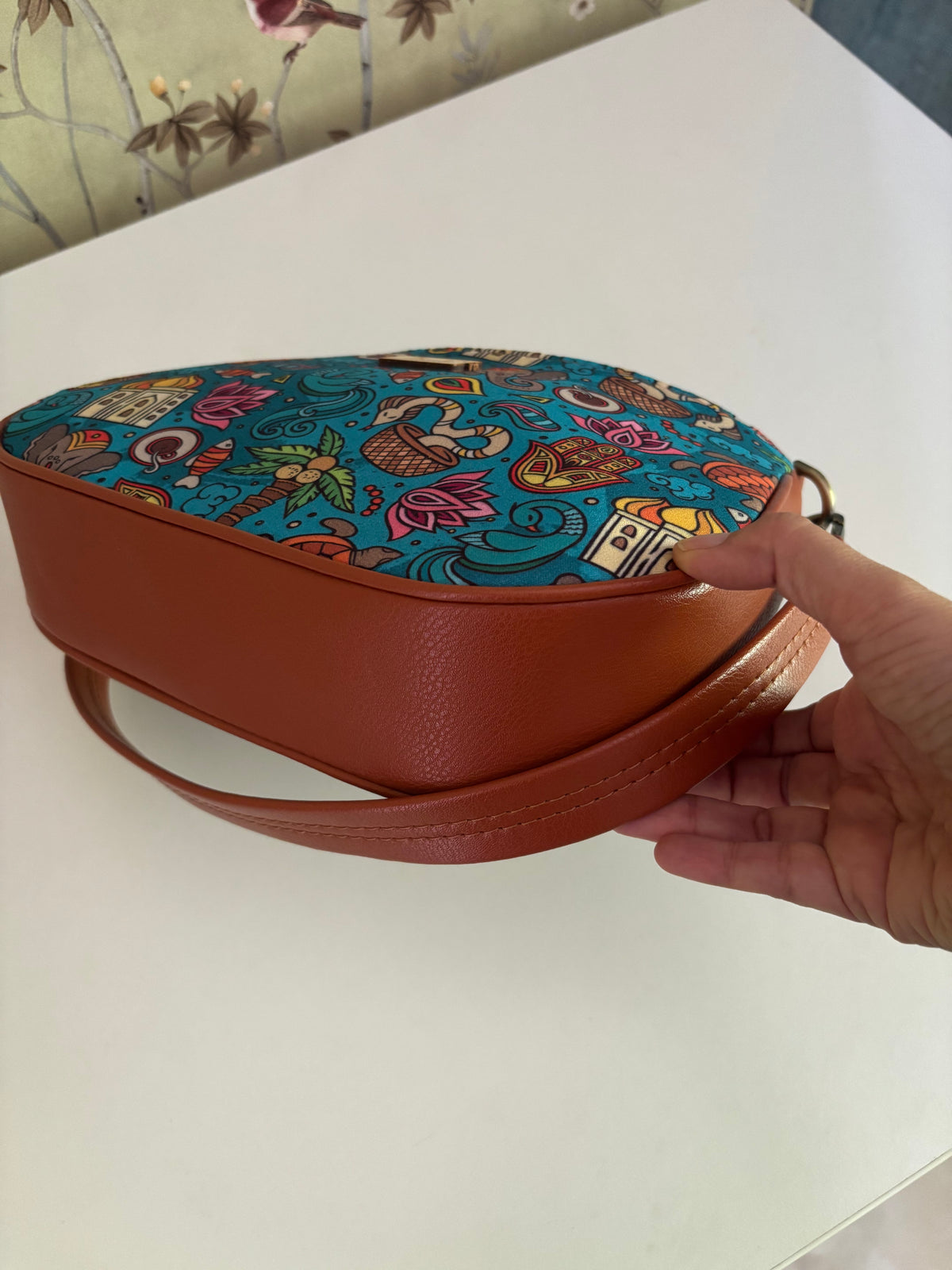 India Print Baguette Bag from below, showing the tan faux leather sides and clip-on strap