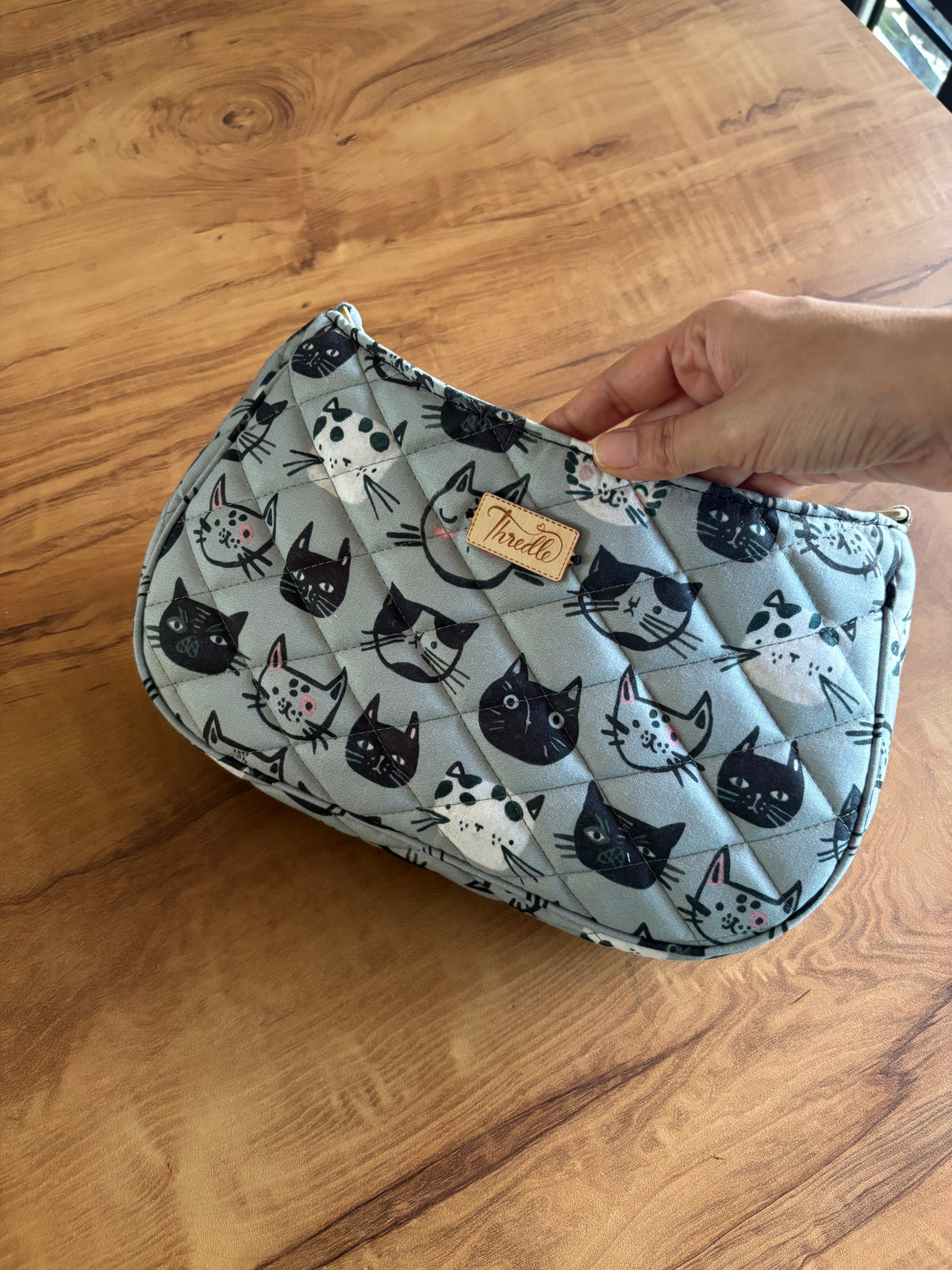 Kitty Faces Quilted Baguette Bag held in hand: grey quilted cotton with cat faces
