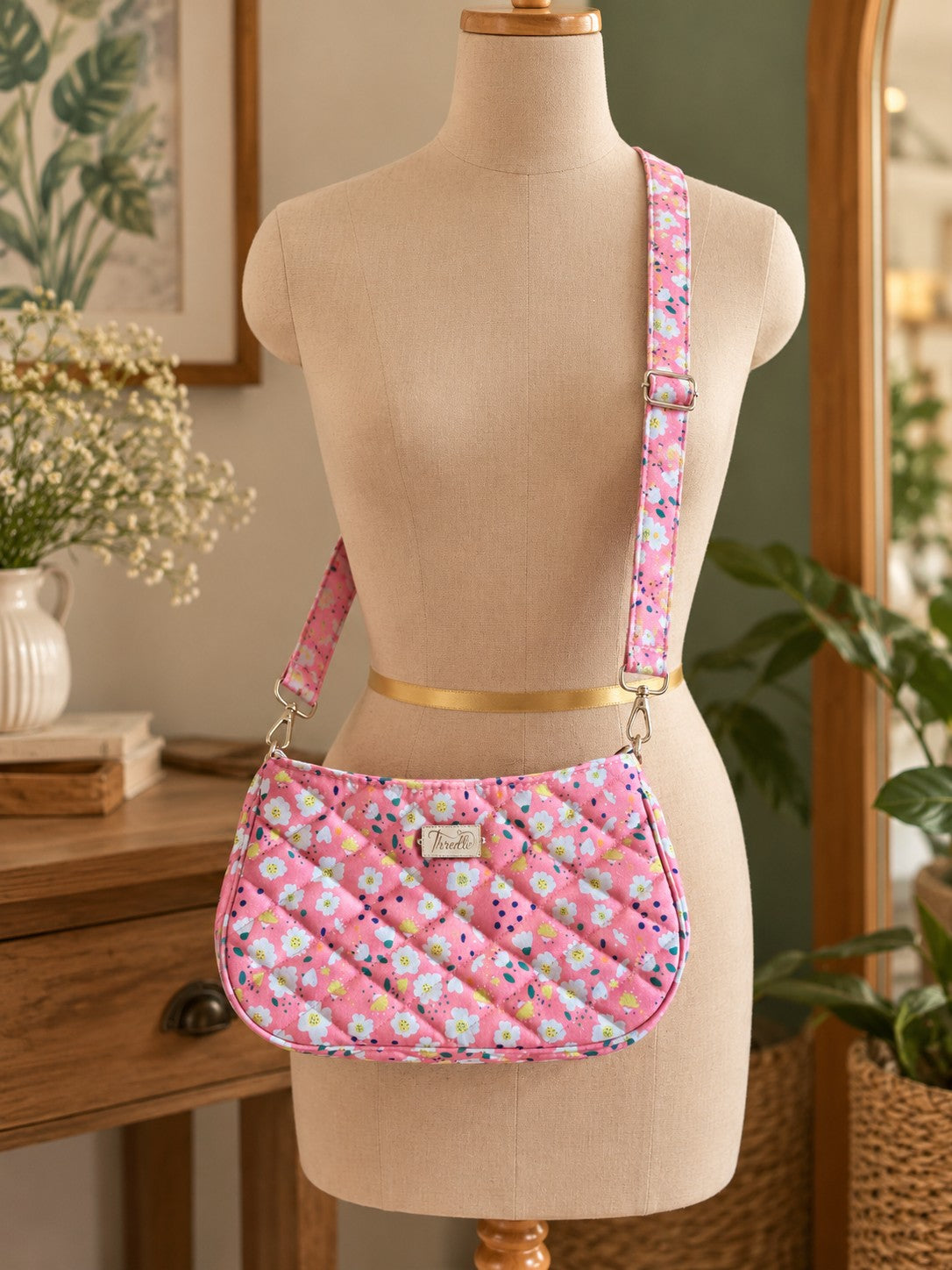Pink Daisy Quilted Baguette Bag worn crossbody on a dress form, with its matching adjustable strap