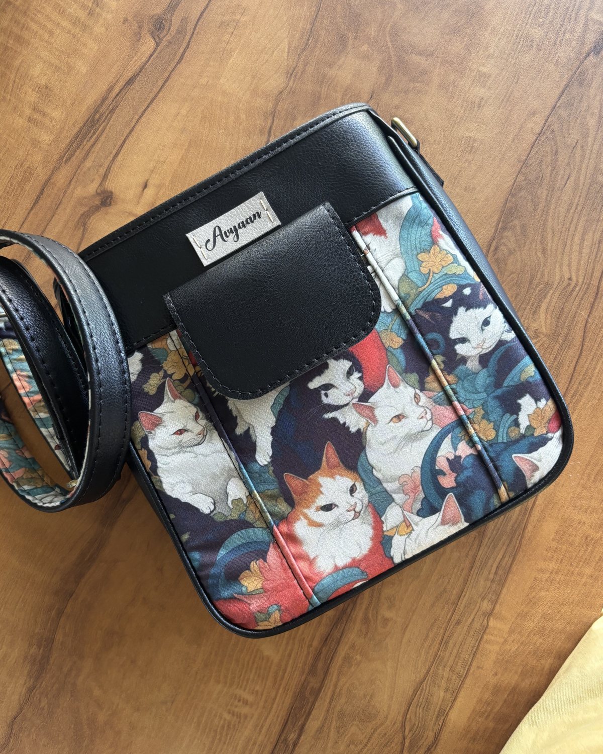 Cat print crossbody bag with a black faux leather flap pocket and a name tag